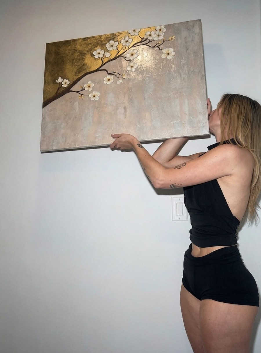 Katelyn Dowdle holding one of her gold and blossom paintings